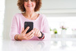 © Krakenimages.com - Close up of senior woman using smartphone over white table smiling confident