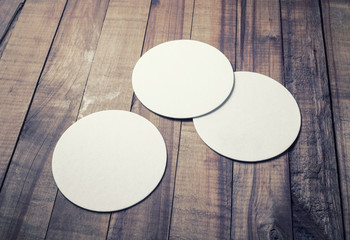 Three blank white beer coasters on wooden background. Responsive design mockup.