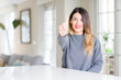 © Krakenimages.com - Young beautiful woman wearing winter sweater at home showing and pointing up with finger number one while smiling confident and happy.