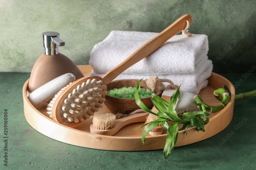 Tray with massage brushes, cosmetics and towels on table