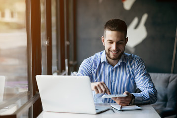 Young man drawing template for the web site associated with digital marketing, current trends and tendencies of UX / UI design. Businessman who rules his company remotely, like a freelancer