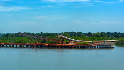 Poster - Outdoor incline large covered conveyor with rubber belt for transportation from an storage outside area to transhipment into a capesize bulk carrier ships in the Kamsar, Guinea, Africa.