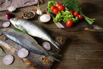 two herring with vegetables and spices on a wooden rustic board