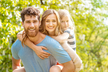 Strong man supporting his family by carrying wife and son piggyback