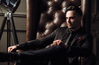 © Cressida studio - Young handsome man posing for a fashion shoot in a studio. Fashion as a lifestyle. Man wearing a beard. Model sitting on a sofa in tuxedo. Successful fashionable businessman. Business look advertising