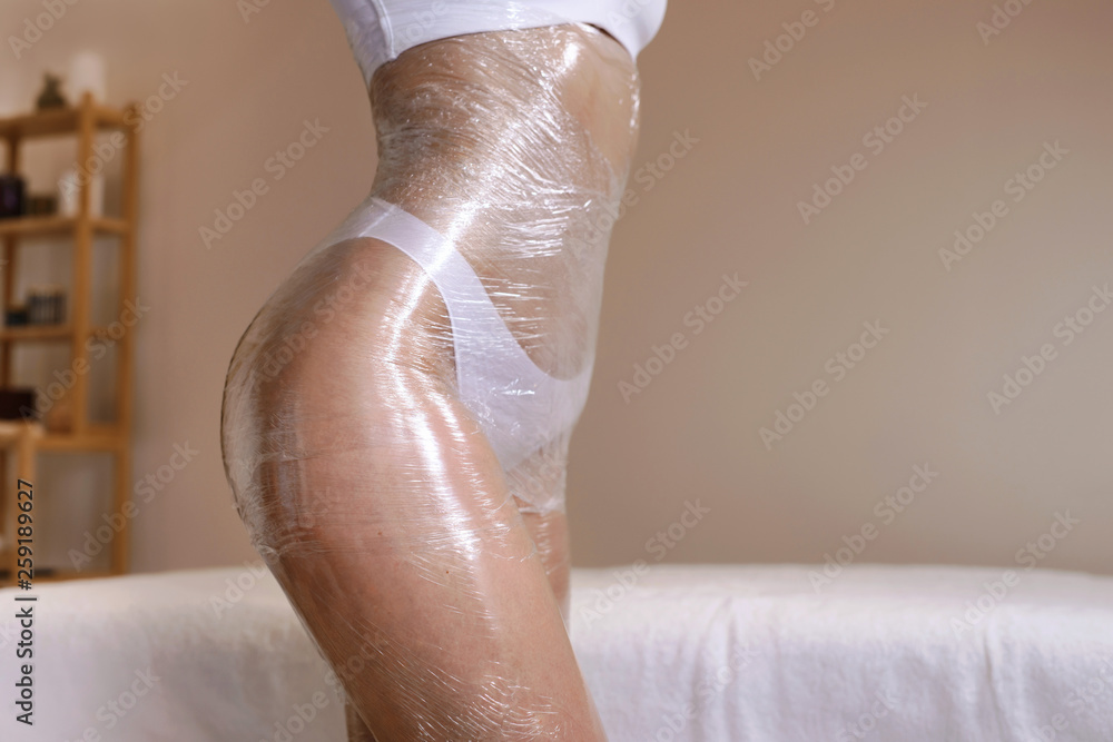 Body wrapping in a spa room. Anti cellulite fat burning procedure in massage salon for perfect slim body and clear skin - obrazy, fototapety, plakaty 