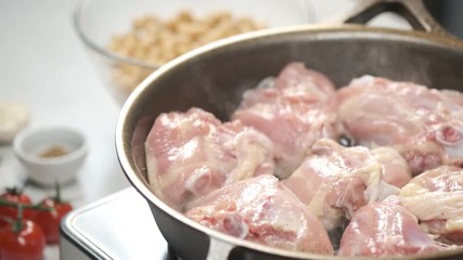 Wall Mural - Cooking chicken raw pieces on hot iron pan by chef hands. Food concept video footage for recipe.