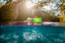 Woman Floats Relaxed Down Lazy Florida River Under Golden Sunlight