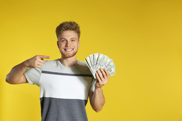 Wall Mural - Young man with money on color background. Space for text