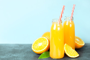 Fresh orange juice in the glass bottle, fresh oranges on dark table.