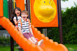 © weedezign - Two kids friends having fun to play together on children's slide at school playground,back to school activity