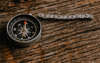 Compass on wood deck with blocks of letters making the word orienteering.