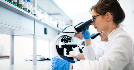 young scientist looking through microscope in laboratory