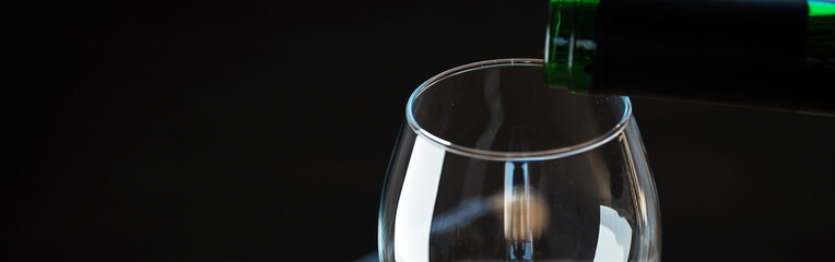 Wall Mural - Pouring red wine into the glass against wooden background