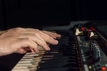 close-up of hand person playing a piano keyboard in spotlights