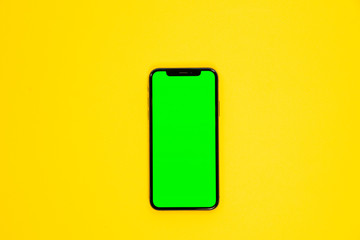 Wall Mural - iPhone XS, smartphone, green screen on Yellow background top view