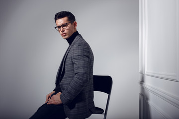 Profile portrait of a handsome, confident, elegantly man in black-gray suit and eyeglasses, posing in studio isolated on white background. Horizontal view.