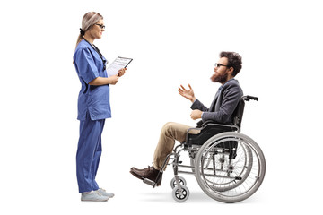 Wall Mural - Young female nurse talking to a bearded man in a wheelchair