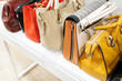 © B@rmaley - Close up collection of woman feminine handbags, standing in a row on shelf