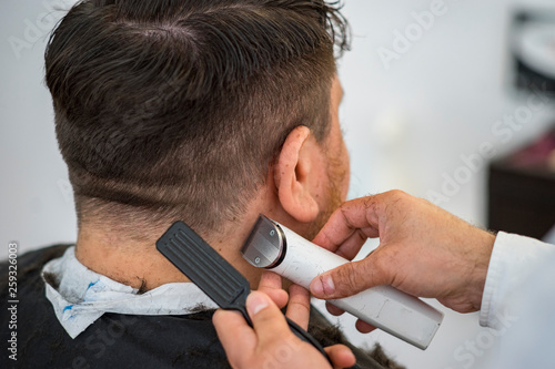 Client Having His Hair Cut In A Barber Shop Where The Hair Dresser Is Using A Brush And A Hair Clipper On The Mans Back Head Buy This Stock Photo And