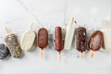 Assortment Of Various Popsicle Ice Cream, Vanilla And Chocolate, With Nuts, On A Dark Concrete Background With Ice, Copy Space Top View