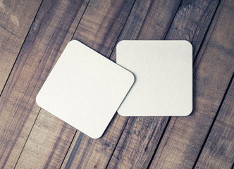 Two blank square beer coasters on vintage wooden background. Flat lay.