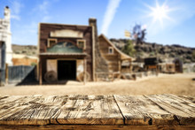 Wooden Old Table Of Free Space For Your Product. Blurred Background Of Wild West City In America. 
