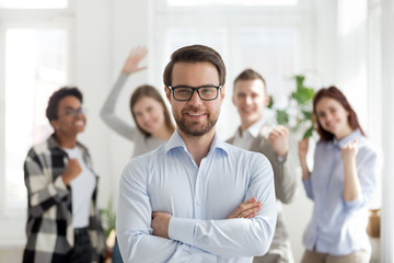 Confident businessman with group of multiracial business people indoors