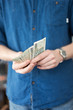 © ingalinder - A man in a casual blue shirt shows or counts a lot of Polish money