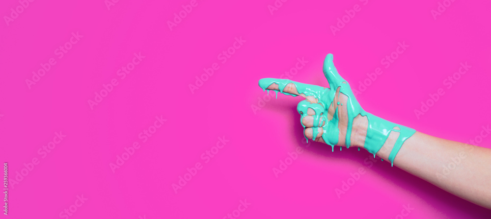 female hand in the paint flowing down the finger shows the direction on a colored background, creative idea of advertising, a gesture of clicking - obrazy, fototapety, plakaty 