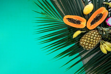  tropical fruits lie on palm leaves near the pool