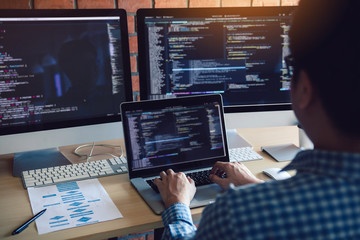 Rear view of software developers is sitting serious analyzing data on the computer screen.