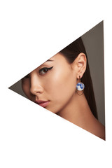 Wall Mural - Cropped side geometric portrait of Asian woman with black flicks, tilting her head. The lady is wearing long earrings with blue smoky pattern, looking at camera behind triangle-shaped foreground.