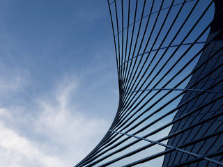 Wall Mural - 3D stimulate of high rise curve glass building and dark steel window system on blue clear sky background,Business concept of future architecture,lookup to the angle of the corner building.