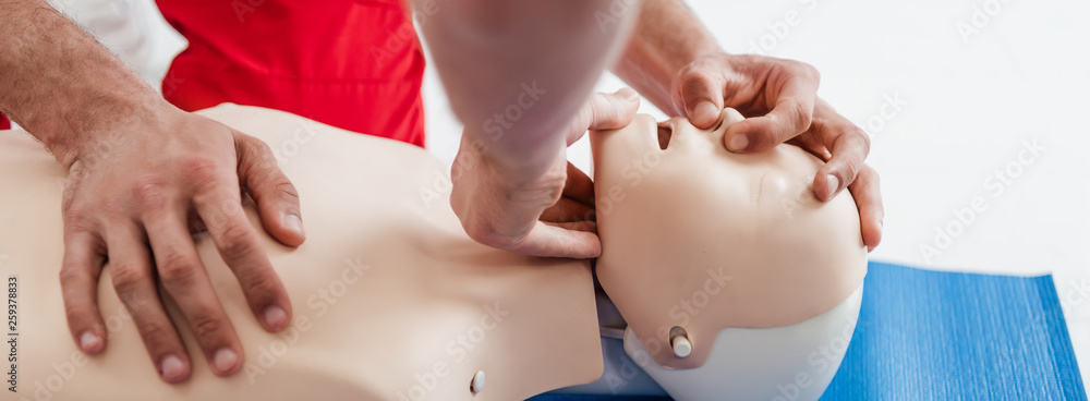 panoramic shot of men practicing cpr technique on dummy during first aid training - obrazy, fototapety, plakaty 