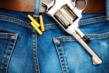 Wall Mural - revolver with cartridges on old blue jeans