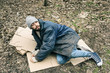 © New Africa - Poor homeless man lying on ground in city park