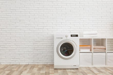 Modern Washing Machine Near Brick Wall In Laundry Room Interior, Space For Text
