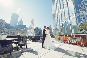 Wall Mural - Elegant bride in a white dress and veil. Handsome groom in a blue suit. Couple in a big town