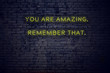 © iushakovsky - Positive inspiring quote on neon sign against brick wall you are amazing remember that