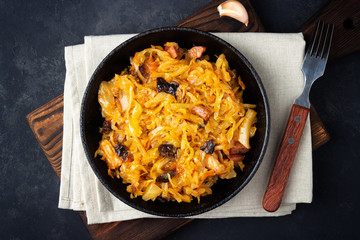 Wall Mural - Traditional dish of polish cuisine - Bigos from fresh cabbage, meat and prunes. Top view. Dark background.