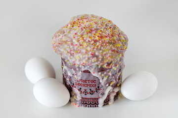 Traditional Russian Easter cake kulich, with white eggs isolated on off-white background