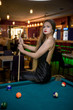 © RomanR - Woman with cue sitting on billiard table