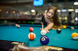 © RomanR - Young and beautiful woman in pub playing billiard
