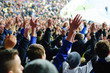 Football fans raising hands, chanting, supporting national team at stadium