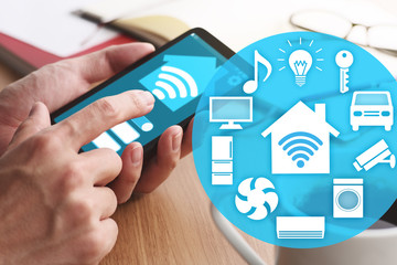 Aufkleber - Smart home and IOT concept. Smartphone and many icons.Closeup of male hands touching smartphone screen for using smart home app at table.