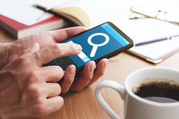 Aufkleber - Closeup of male hands touching smartphone screen for internet search at table. Magnifying glass icon on smartphone screen.