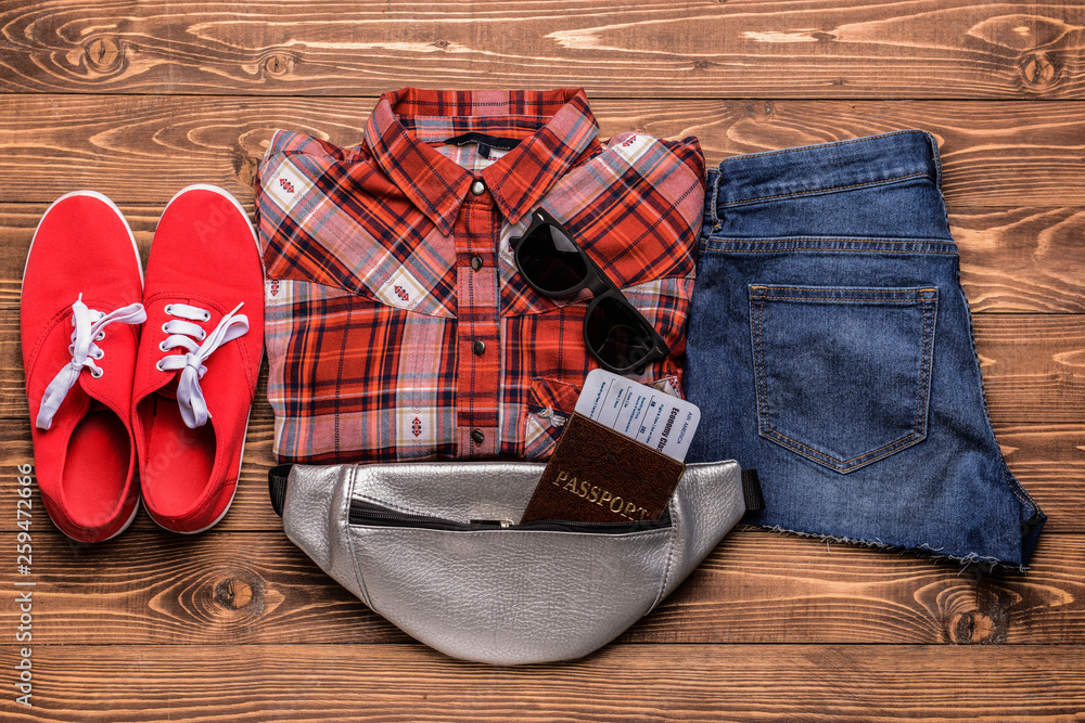 Female clothes with documents and sunglasses on wooden background