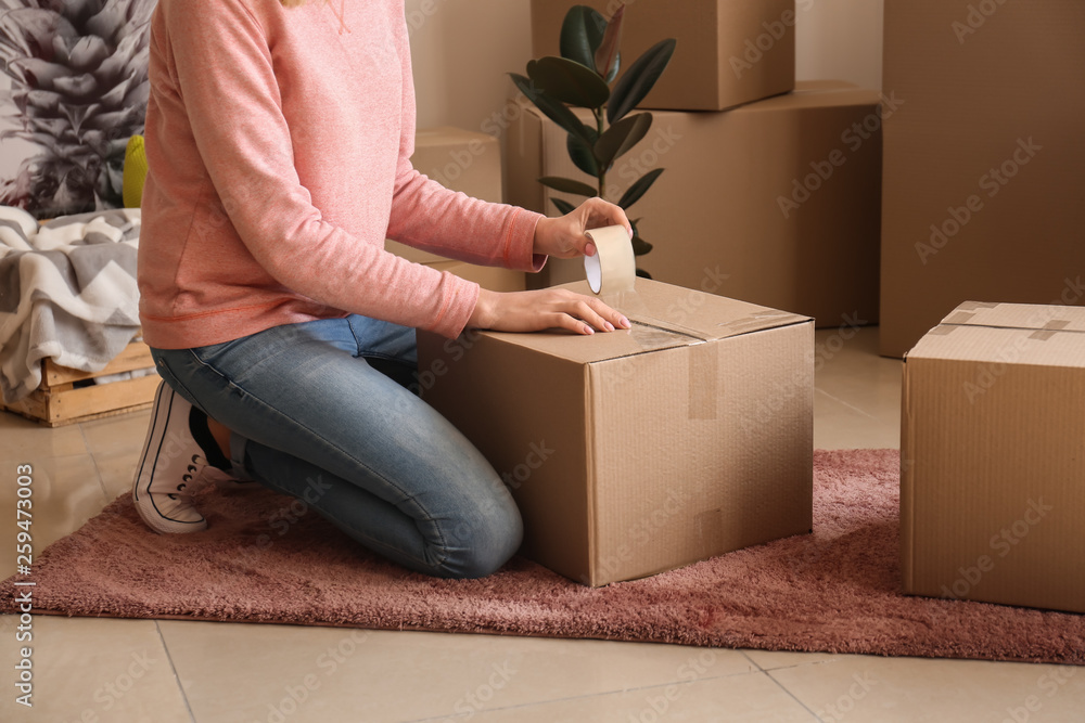 Young woman packing belongings in room