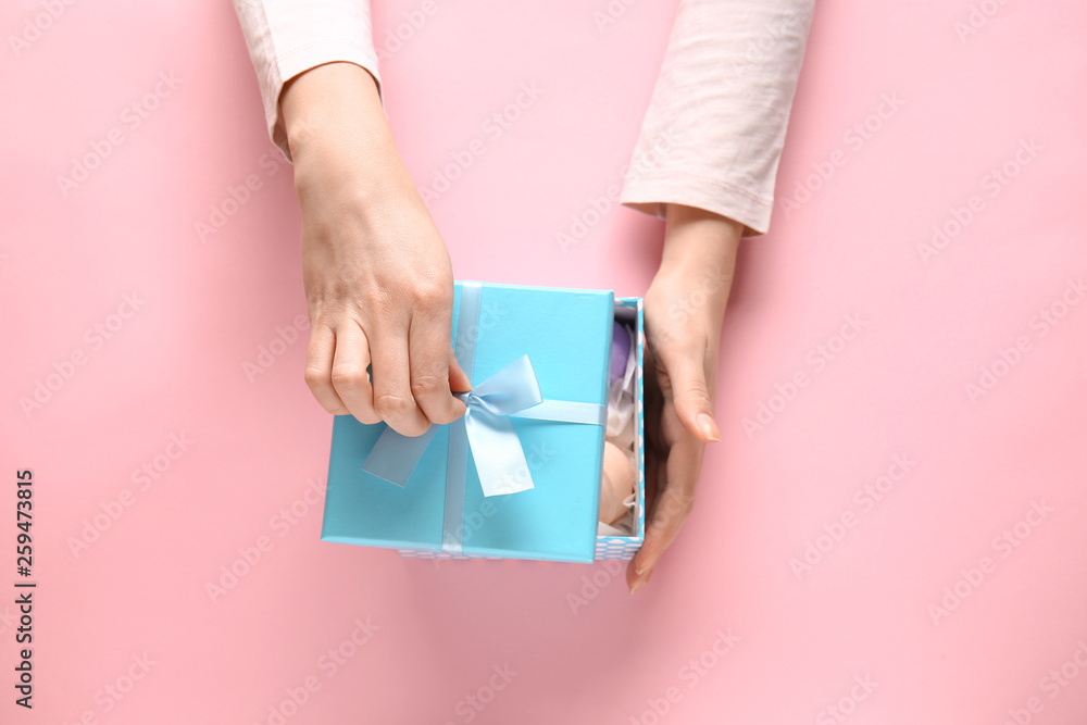 Female hands with gift box on color background